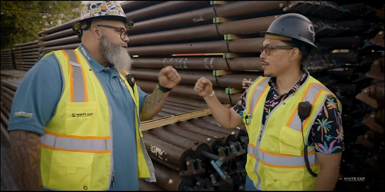 Two workers wearing branded high-visibility safety vests on a job site